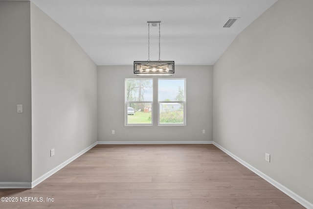 spare room with a chandelier and light hardwood / wood-style floors