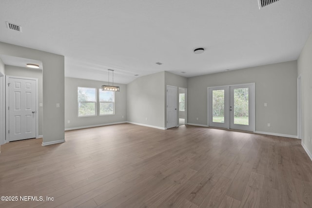 unfurnished living room with a wealth of natural light, french doors, and light wood-type flooring