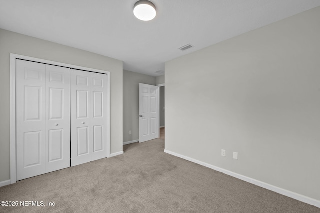 unfurnished bedroom featuring light colored carpet and a closet