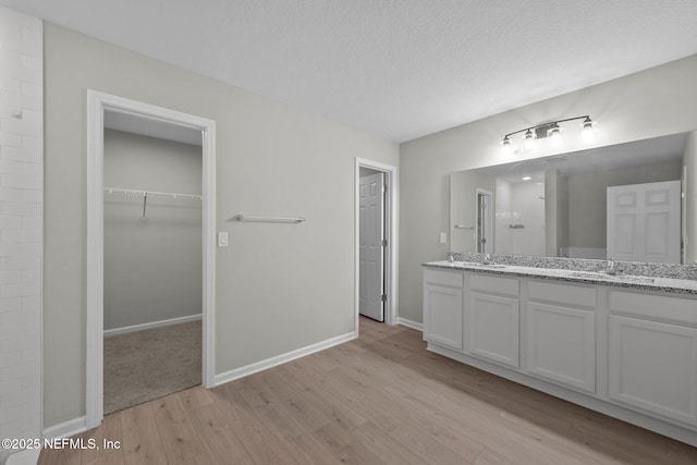 bathroom with hardwood / wood-style floors, vanity, walk in shower, and a textured ceiling