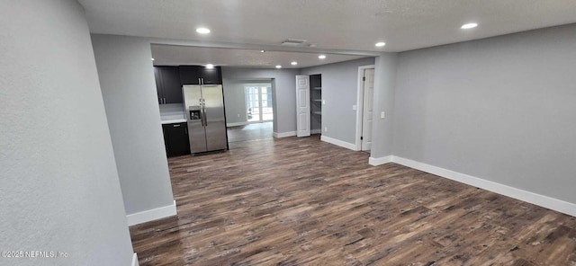 interior space with dark wood-style flooring, recessed lighting, stainless steel fridge with ice dispenser, dark cabinetry, and baseboards