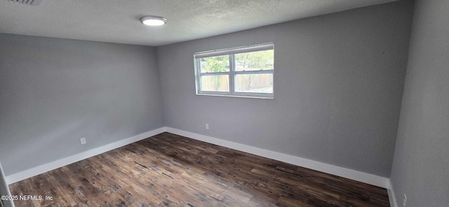 unfurnished room featuring a textured ceiling, dark wood-type flooring, and baseboards