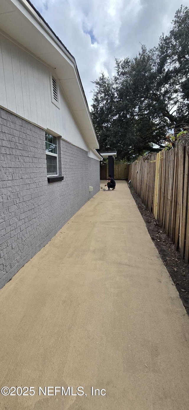 view of side of property with brick siding, a patio area, and a fenced backyard