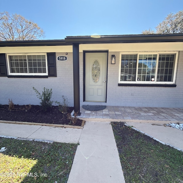 view of exterior entry featuring brick siding