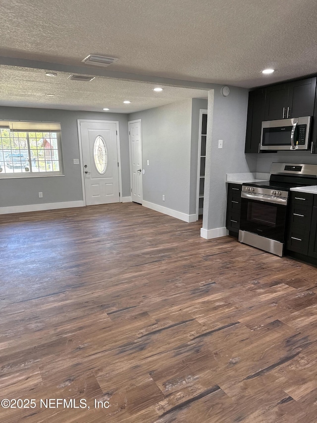 kitchen featuring open floor plan, stainless steel appliances, and dark cabinets