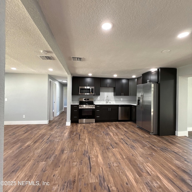 kitchen featuring light countertops, visible vents, appliances with stainless steel finishes, a sink, and dark cabinets