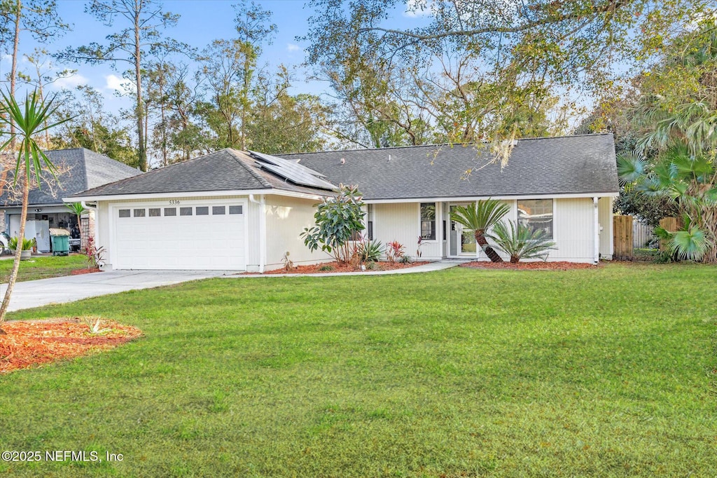 single story home featuring a front lawn, a garage, and solar panels