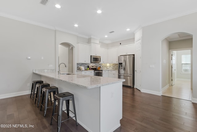 kitchen featuring sink, white cabinetry, stainless steel appliances, light stone counters, and kitchen peninsula