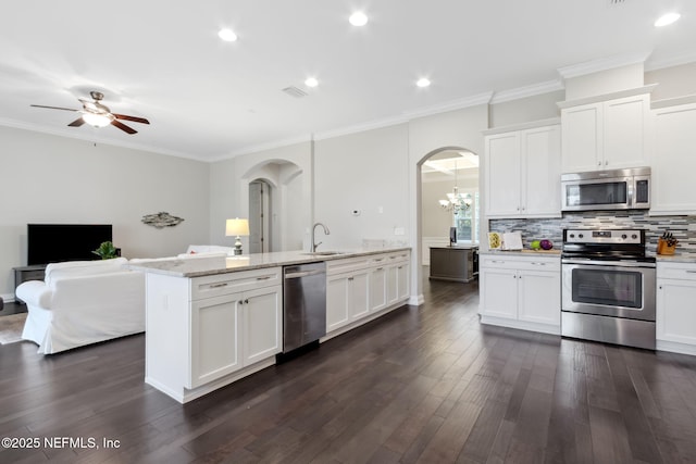 kitchen featuring sink, appliances with stainless steel finishes, tasteful backsplash, light stone countertops, and white cabinets