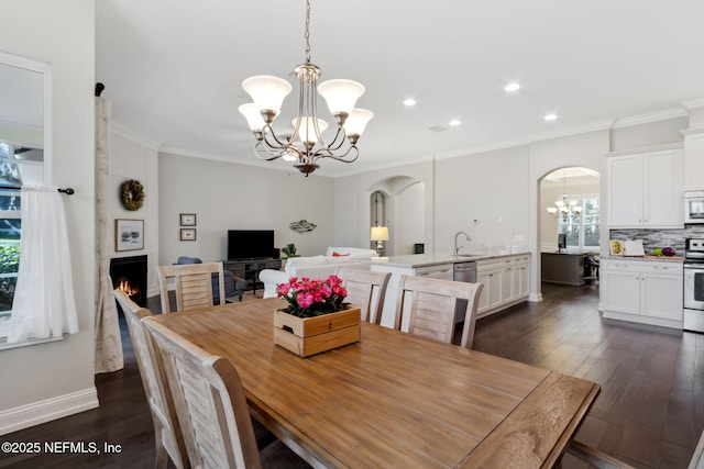 dining area with an inviting chandelier, sink, dark wood-type flooring, and ornamental molding