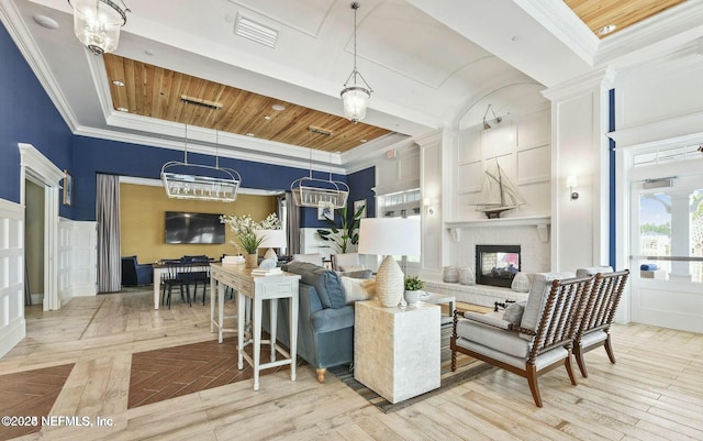 living room featuring a chandelier, wood ceiling, crown molding, and a brick fireplace