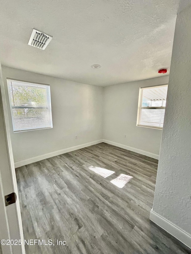 empty room featuring wood-type flooring and a textured ceiling