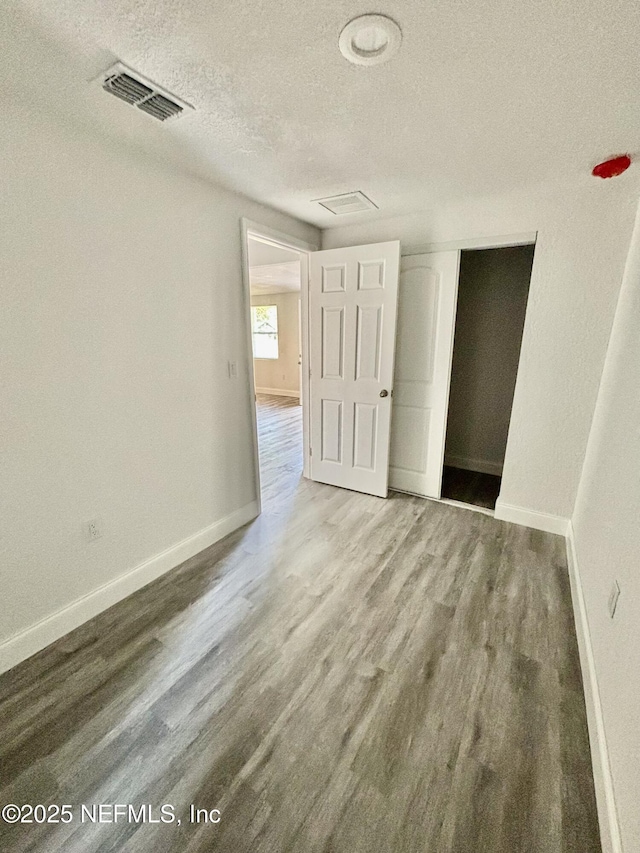 spare room featuring a textured ceiling and hardwood / wood-style flooring