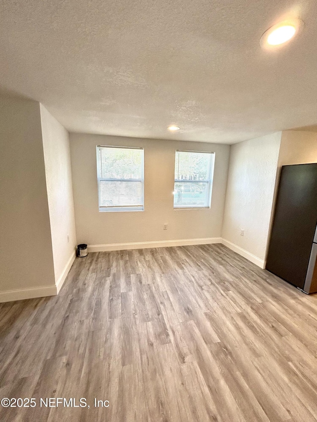 spare room with light hardwood / wood-style floors and a textured ceiling