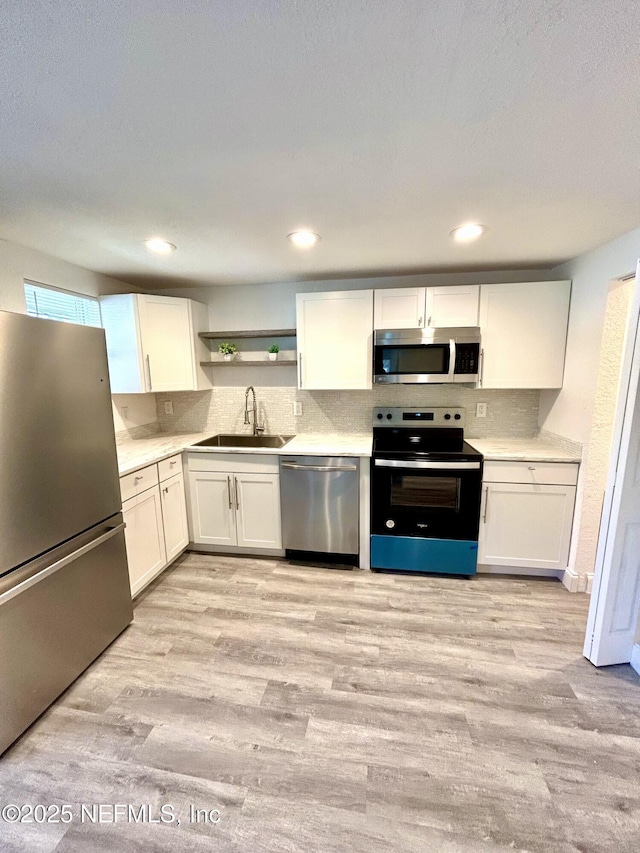 kitchen with stainless steel appliances, white cabinetry, and sink