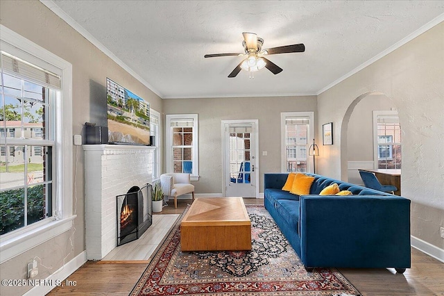 living room featuring hardwood / wood-style flooring, a healthy amount of sunlight, a textured ceiling, and a brick fireplace