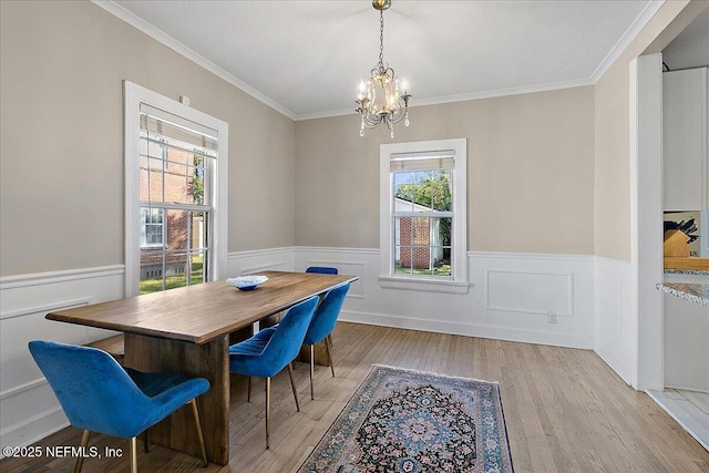 dining space featuring a wealth of natural light, crown molding, an inviting chandelier, and light wood-type flooring