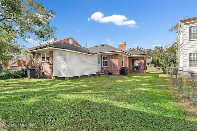 rear view of house with a lawn and central AC unit