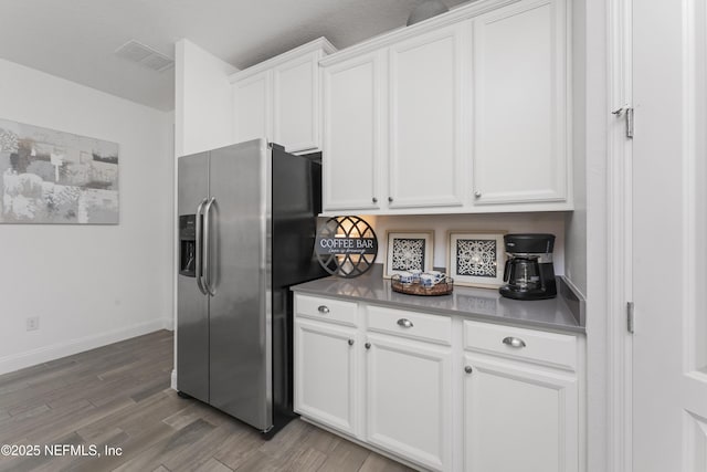 kitchen with white cabinets, stainless steel fridge, and hardwood / wood-style floors