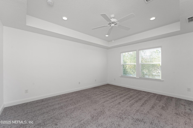 carpeted empty room featuring ceiling fan and a raised ceiling