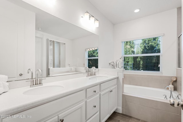 bathroom with vanity and tiled tub