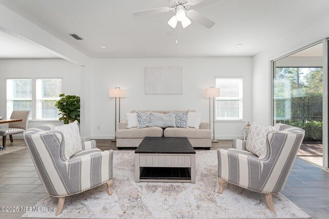 living room featuring ceiling fan, plenty of natural light, and light hardwood / wood-style floors