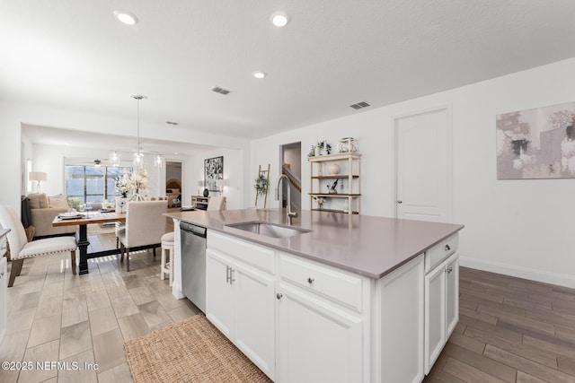 kitchen featuring sink, dishwasher, white cabinetry, hanging light fixtures, and an island with sink