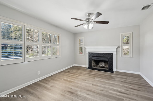 unfurnished living room with a wealth of natural light, a fireplace, ceiling fan, and hardwood / wood-style floors