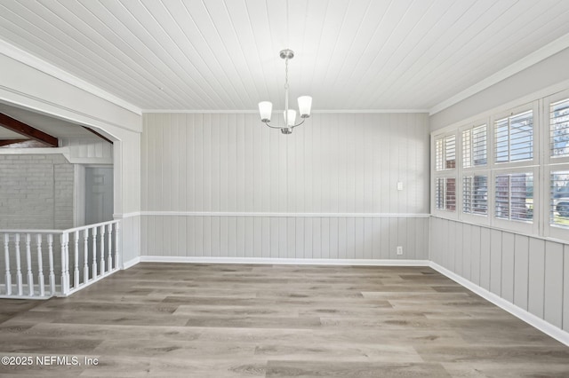 empty room featuring wooden ceiling, wood-type flooring, a notable chandelier, and ornamental molding