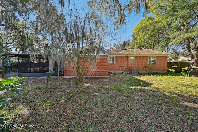 back of house with central air condition unit, a sunroom, and a yard