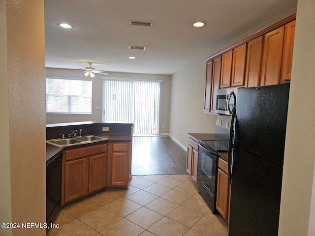 kitchen featuring a textured ceiling, ceiling fan, sink, black appliances, and light tile patterned floors