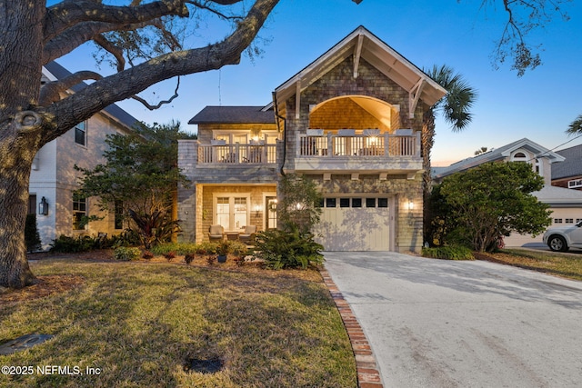 view of front of home with concrete driveway, a yard, an attached garage, and a balcony