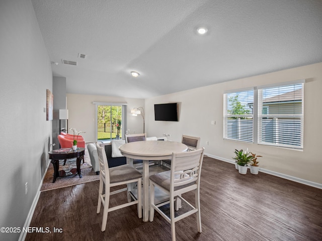 dining space with a textured ceiling and dark wood-type flooring