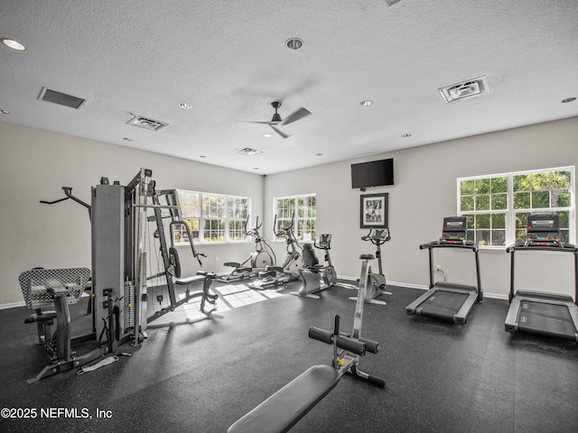 gym featuring ceiling fan and a textured ceiling