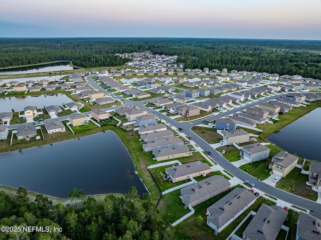 aerial view at dusk featuring a water view