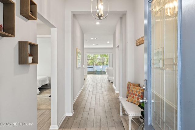 hall featuring an inviting chandelier and light hardwood / wood-style floors