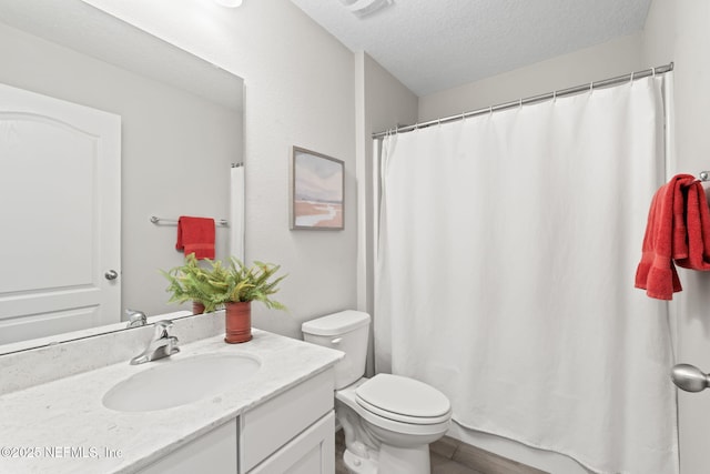 bathroom with vanity, toilet, and a textured ceiling