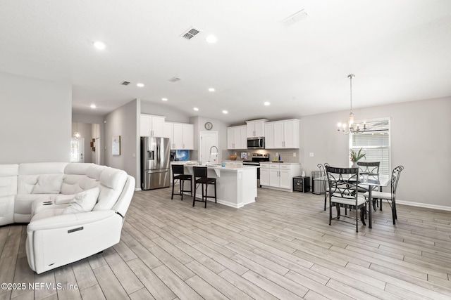 living room with lofted ceiling, light hardwood / wood-style floors, and a notable chandelier