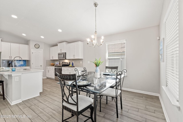 dining space featuring vaulted ceiling, an inviting chandelier, and sink