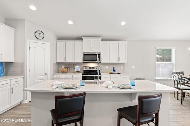 kitchen with an island with sink and appliances with stainless steel finishes