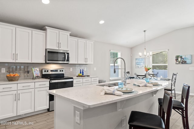 kitchen with sink, white cabinetry, decorative light fixtures, a center island with sink, and stainless steel appliances