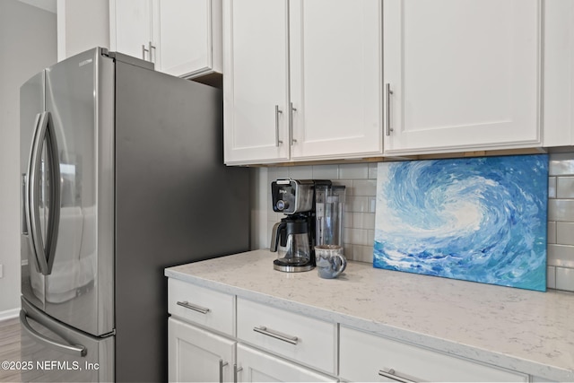 kitchen with white cabinetry, light stone countertops, and stainless steel fridge with ice dispenser