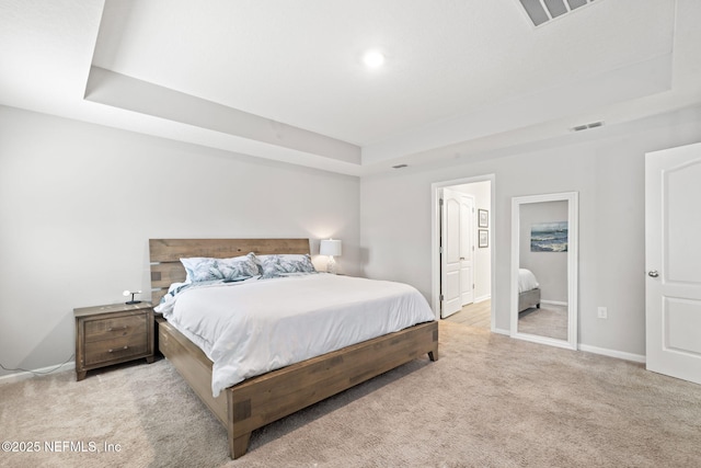 bedroom featuring light carpet and a raised ceiling