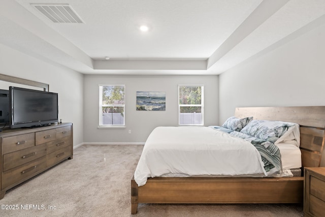 carpeted bedroom with a raised ceiling and multiple windows