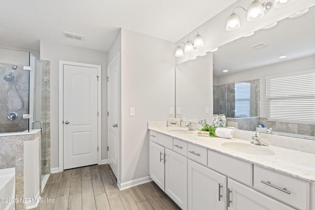 bathroom featuring vanity, independent shower and bath, and a textured ceiling