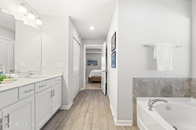 bathroom with wood-type flooring, a bath, and vanity