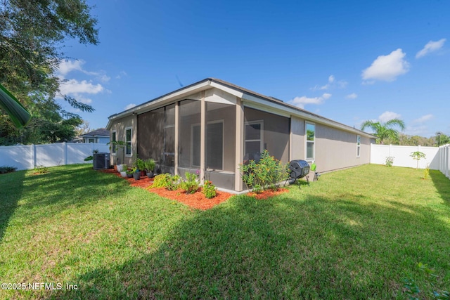 rear view of house with a sunroom, cooling unit, and a lawn