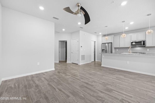 unfurnished living room featuring ceiling fan and light hardwood / wood-style floors