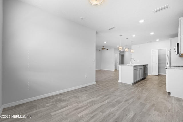 kitchen featuring white cabinetry, hanging light fixtures, appliances with stainless steel finishes, an island with sink, and light hardwood / wood-style floors