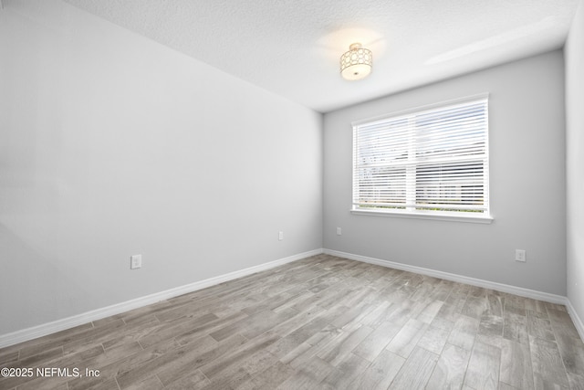 unfurnished room featuring light hardwood / wood-style floors and a textured ceiling